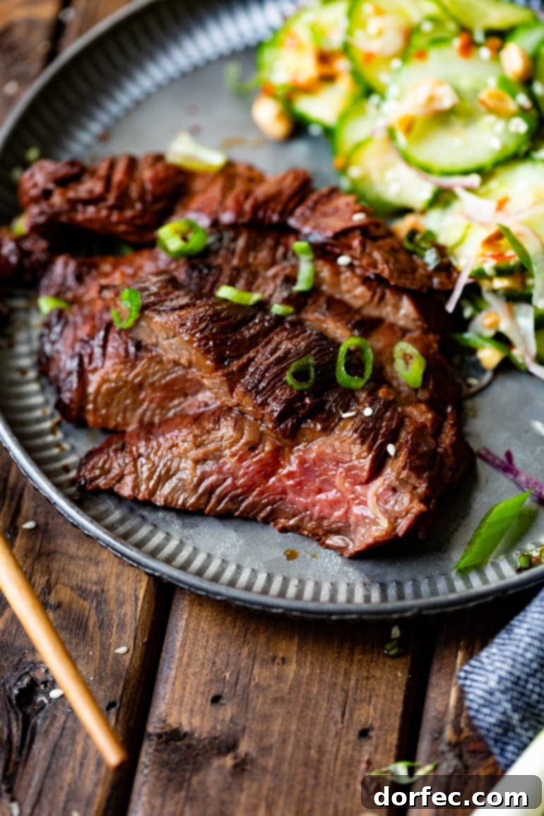 a photo of thin slices of asian marinated flank steaks topped with chopped scallions with a side of cucumber salad.