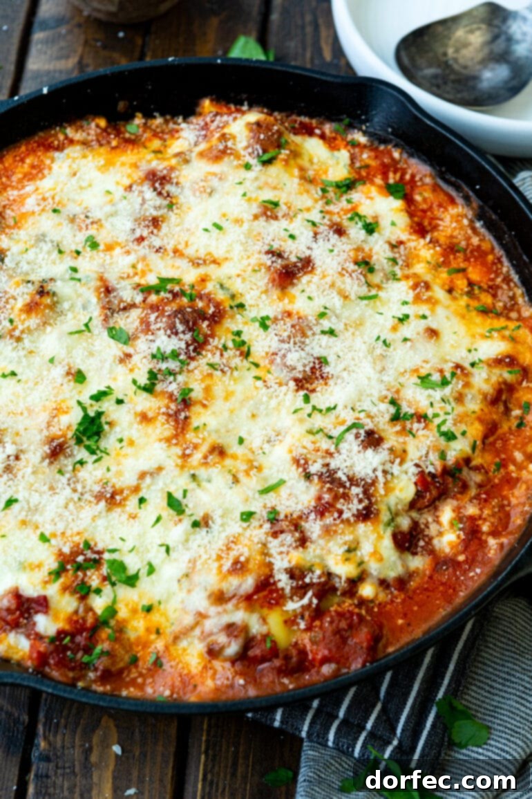Effortless Skillet Ravioli Lasagna 7 A photo of a cast iron skillet filled with delicious ravioli lazy lasagna, perfectly topped with melted mozzarella cheese and vibrant chopped parsley, ready for serving.