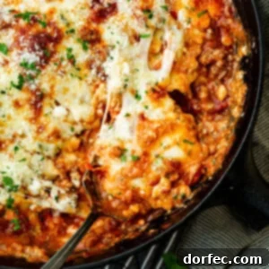 a photo of a serving of skillet lasagna being scooped out of a cast iron skillet