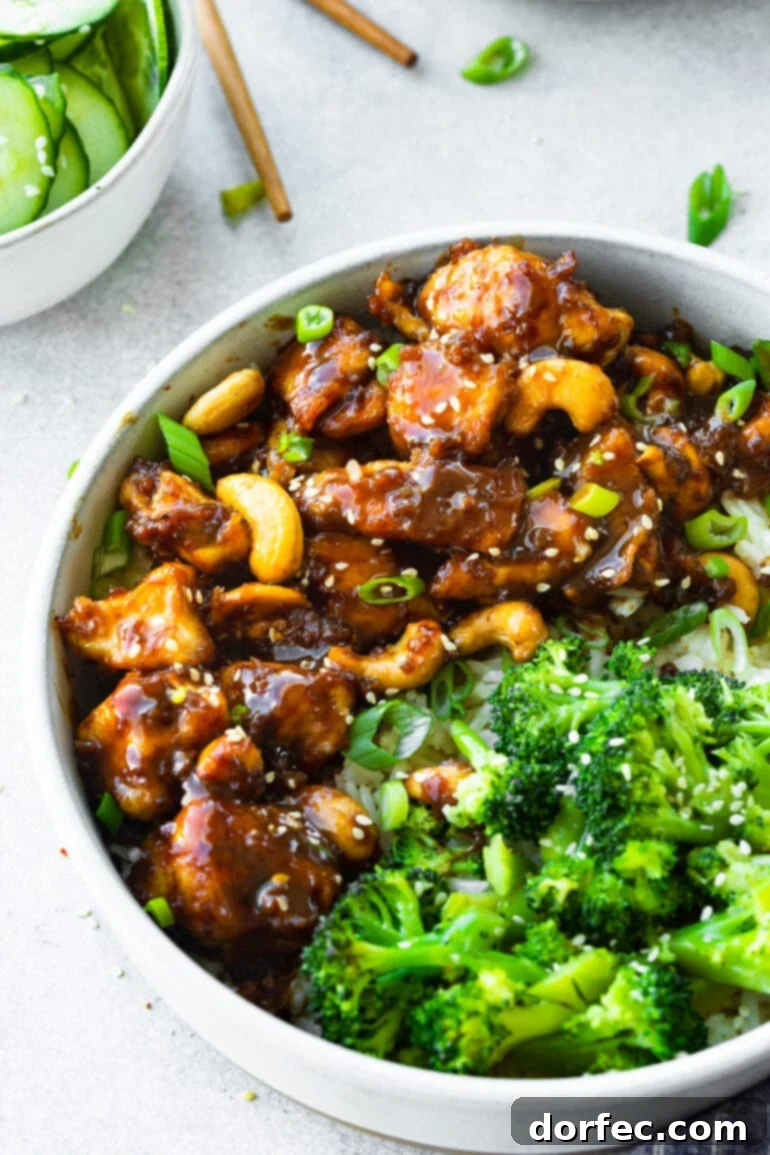 A vibrant bowl of easy cashew chicken, featuring tender chicken pieces, crunchy roasted cashews, and a rich, savory sauce, served alongside a portion of steamed broccoli.