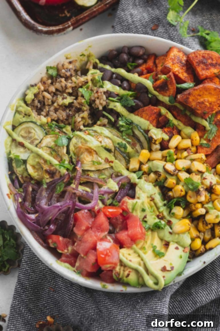 A colorful and wholesome plant-based vegan burrito bowl, generously filled with nutritious brown rice, quinoa, black beans, roasted corn, diced tomatoes, red onions, zucchini, and sweet potatoes.