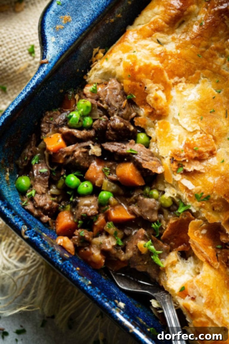 Weekly Meal Plan March 11-17 5 A mouth-watering photo showcasing a generous portion of beef pot pie in a baking dish, with a serving expertly removed to reveal the rich, saucy beef filling brimming with vibrant carrots, tender peas, and sweet onions, all perfectly encased beneath a golden, flaky puff pastry crust.