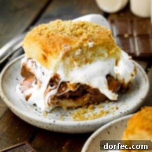A delicious s'mores slider on a small dessert plate, with gooey melted marshmallows and rich chocolate oozing out from sweet Hawaiian rolls.