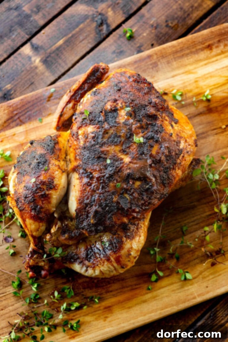 A photo of a perfectly air-fried whole chicken with golden, crispy skin, resting on a rustic wooden board, garnished with fresh herbs.