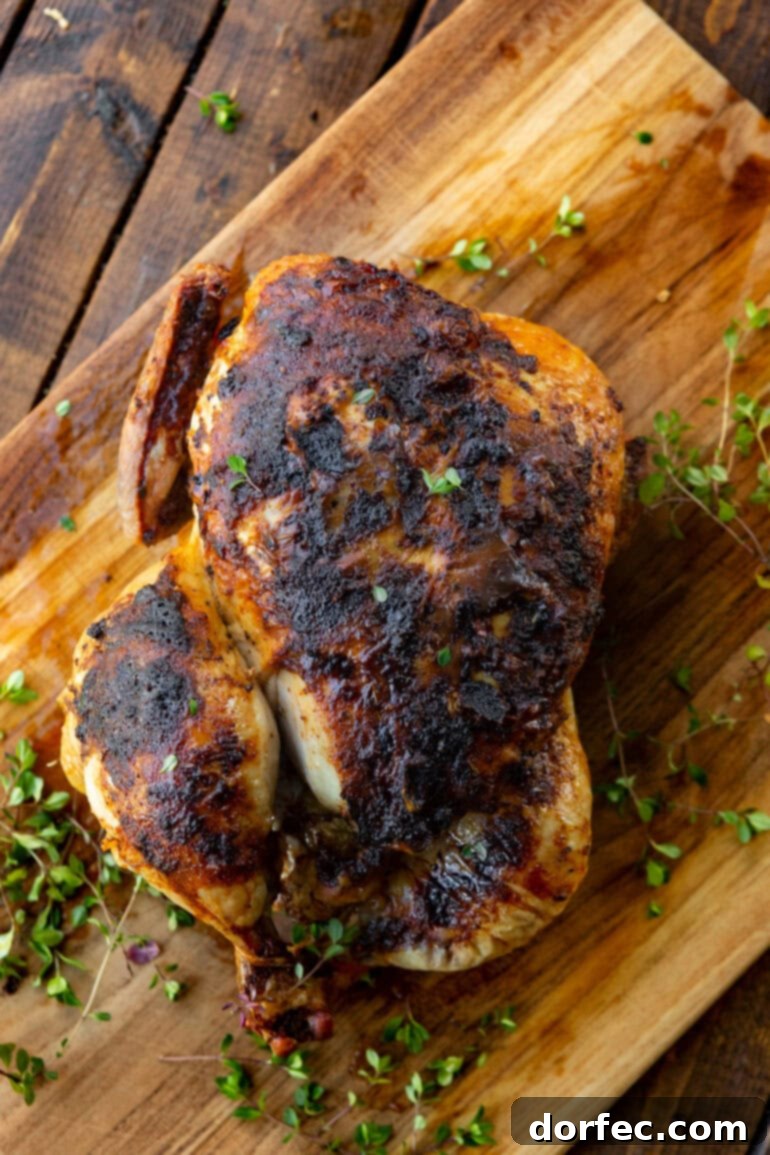 A top-down photo of a beautifully air-fried whole chicken, garnished with fresh thyme, emphasizing its crispy golden skin.