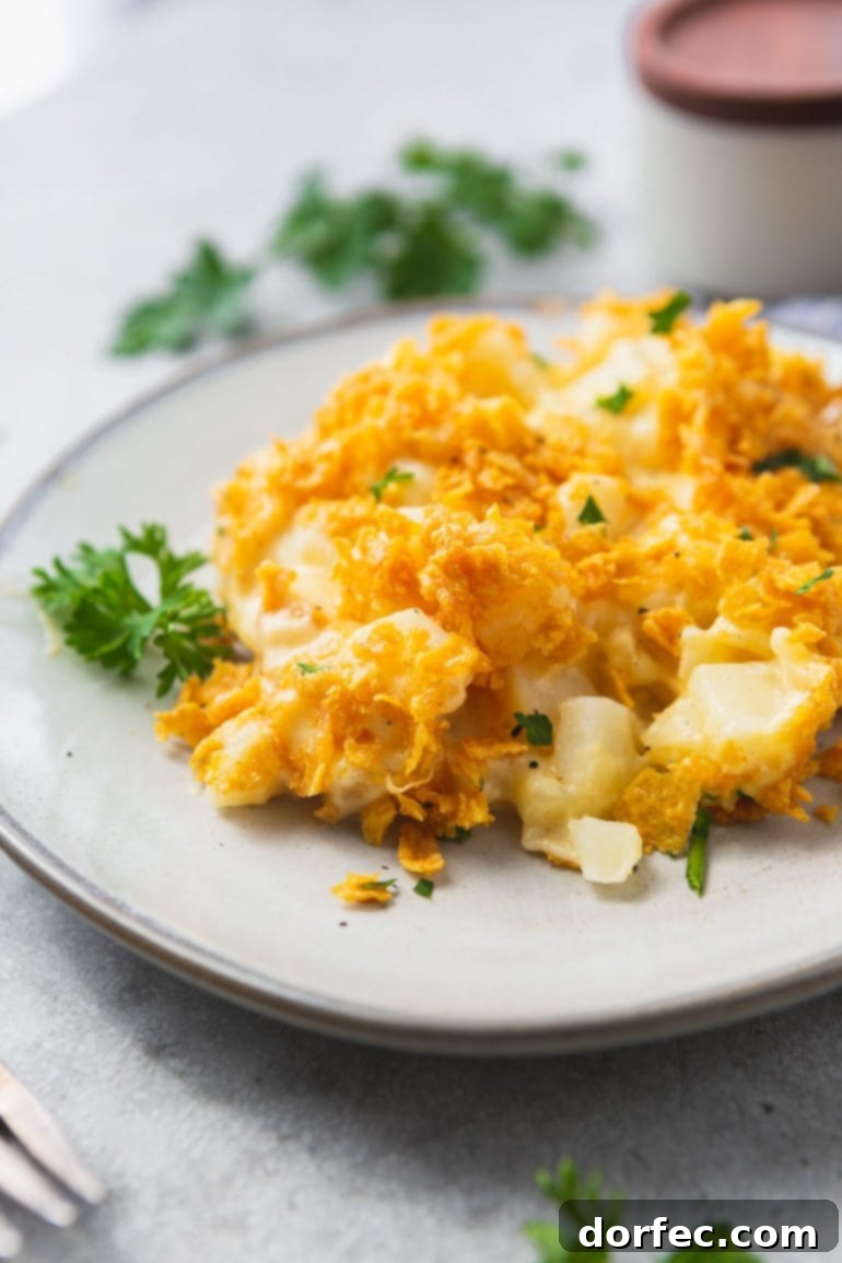 a photo of a serving of cheesy potato casserole on a white plate with golden crunchy topping.