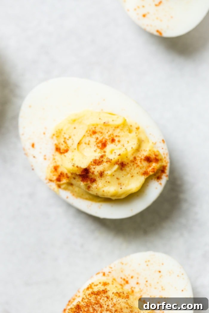 A grey board with a single deviled egg with paprika sprinkled on the top which makes the best deviled eggs ever!