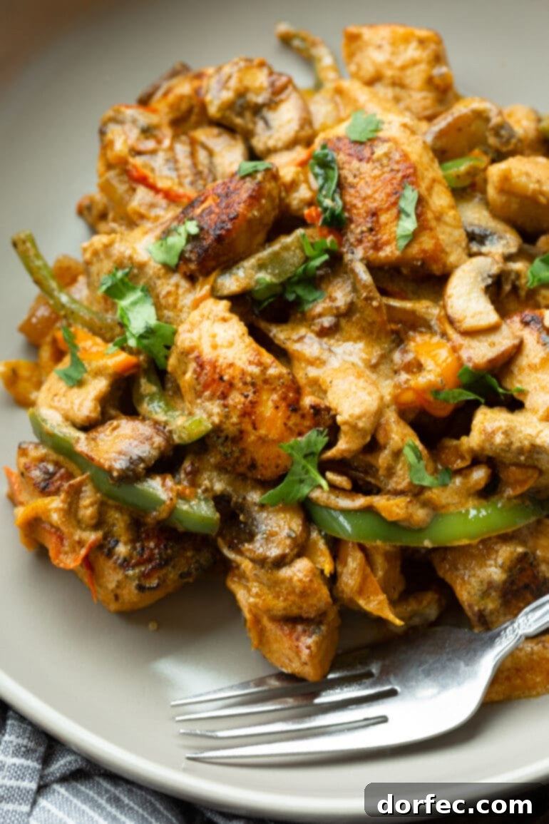 A serving of creamy Pollo a la Crema, garnished with fresh chopped cilantro, on a pristine white dinner plate.