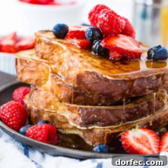 A stack of perfectly golden French toast slices, lightly dusted with powdered sugar, ready for syrup and toppings.