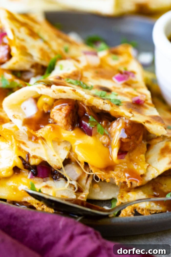 A perfectly golden slice of Teriyaki Chicken Quesadilla, garnished with fresh cilantro and minced red onion, showcasing the melty cheese and flavorful teriyaki chicken filling.