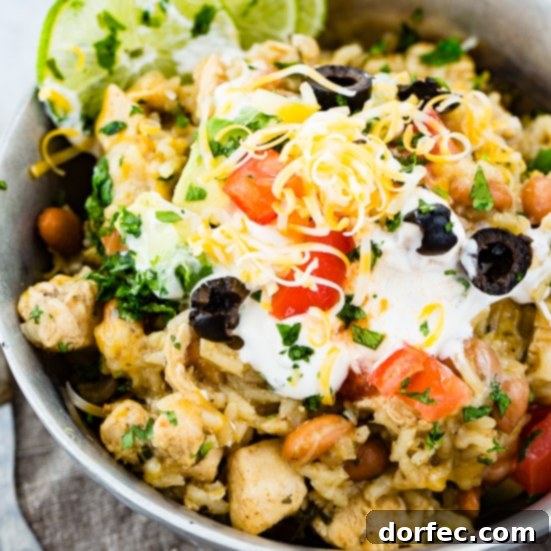 A vibrant Instant Pot cilantro lime chicken burrito bowl, generously topped with creamy sour cream, diced fresh tomatoes, bright cilantro, savory olives, and plenty of melted cheese.