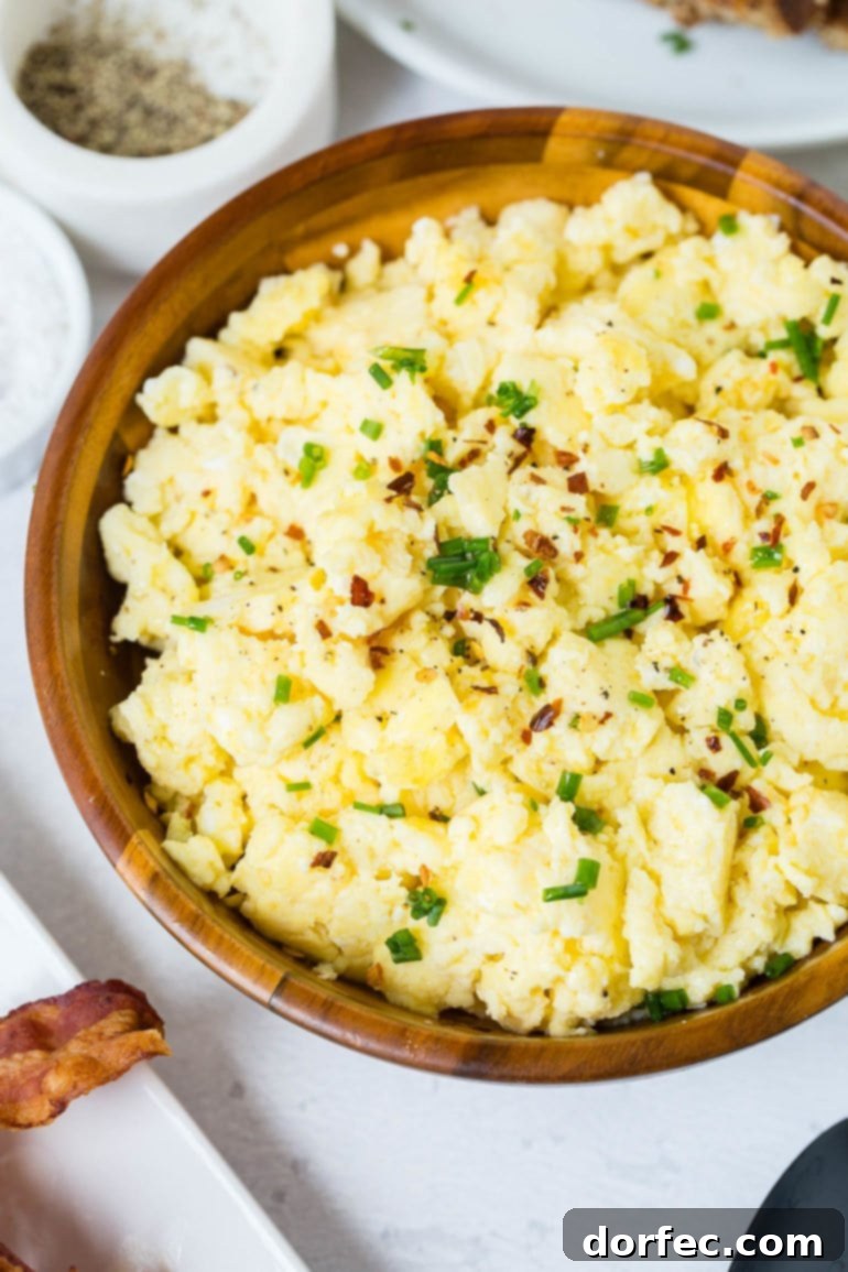 A delightful bowl of light, airy, and fluffy scrambled eggs, elegantly sprinkled with freshly sliced green onions for added flavor and color.