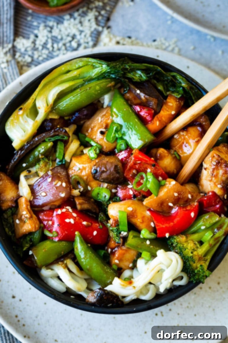 A close-up view of a bowl brimming with colorful chicken stir-fry, showcasing juicy chicken pieces, bright red bell peppers, fresh broccoli florets, vibrant snap peas, earthy mushrooms, and tender bok choy.