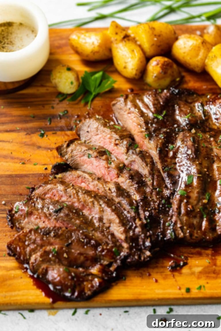 A beautiful cutting board featuring perfectly sliced grilled flank steak, showcasing its tender interior, alongside roasted Yukon gold potatoes, all enhanced by a delicious balsamic marinade.