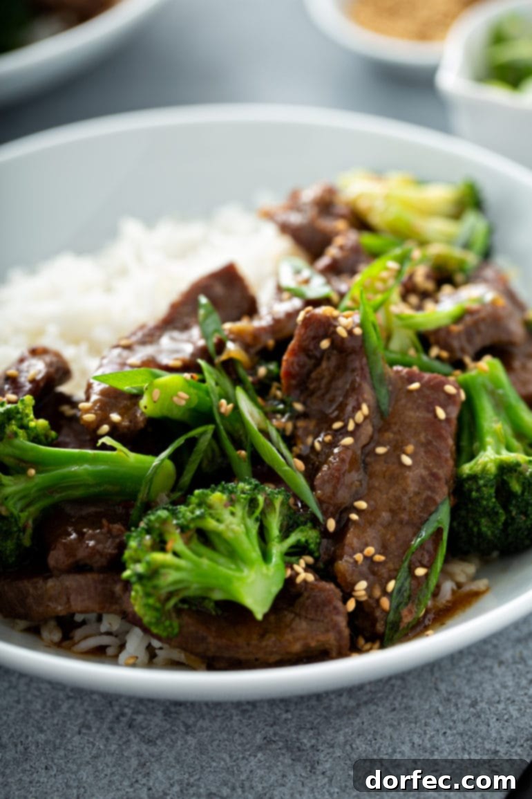 A vibrant plate of Instant Pot Beef & Broccoli, featuring tender beef slices and bright green broccoli florets coated in a glossy sauce, served alongside fluffy white rice.