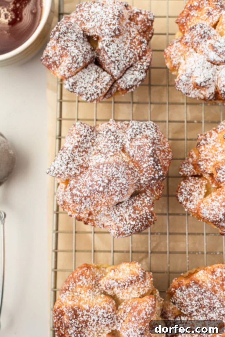 Several perfectly baked French toast muffins, lightly dusted with powdered sugar, cooling on a wire rack, showcasing their inviting golden color and fluffy texture.