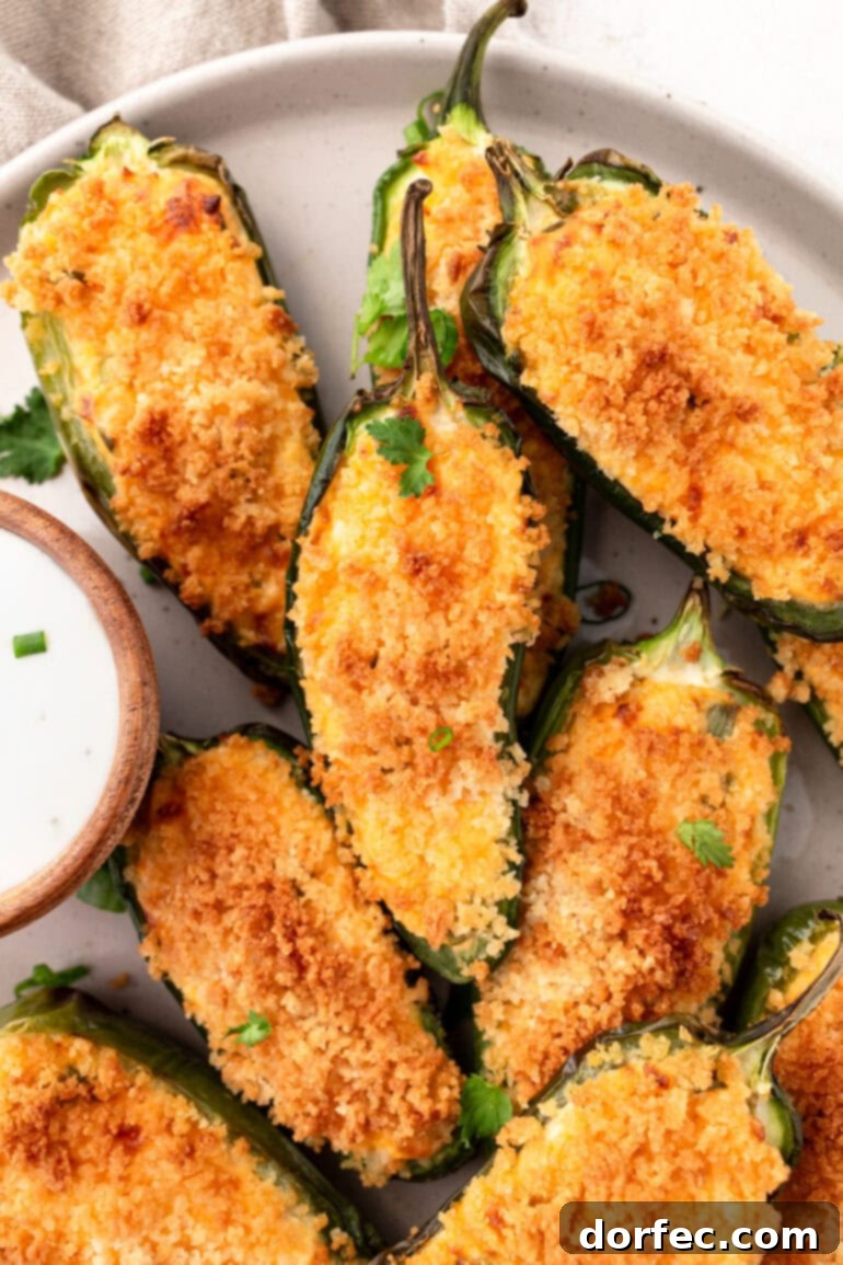 A plate of golden crispy jalapeño poppers sitting next to a small cup of creamy garlic dip, a perfect air fryer recipe.