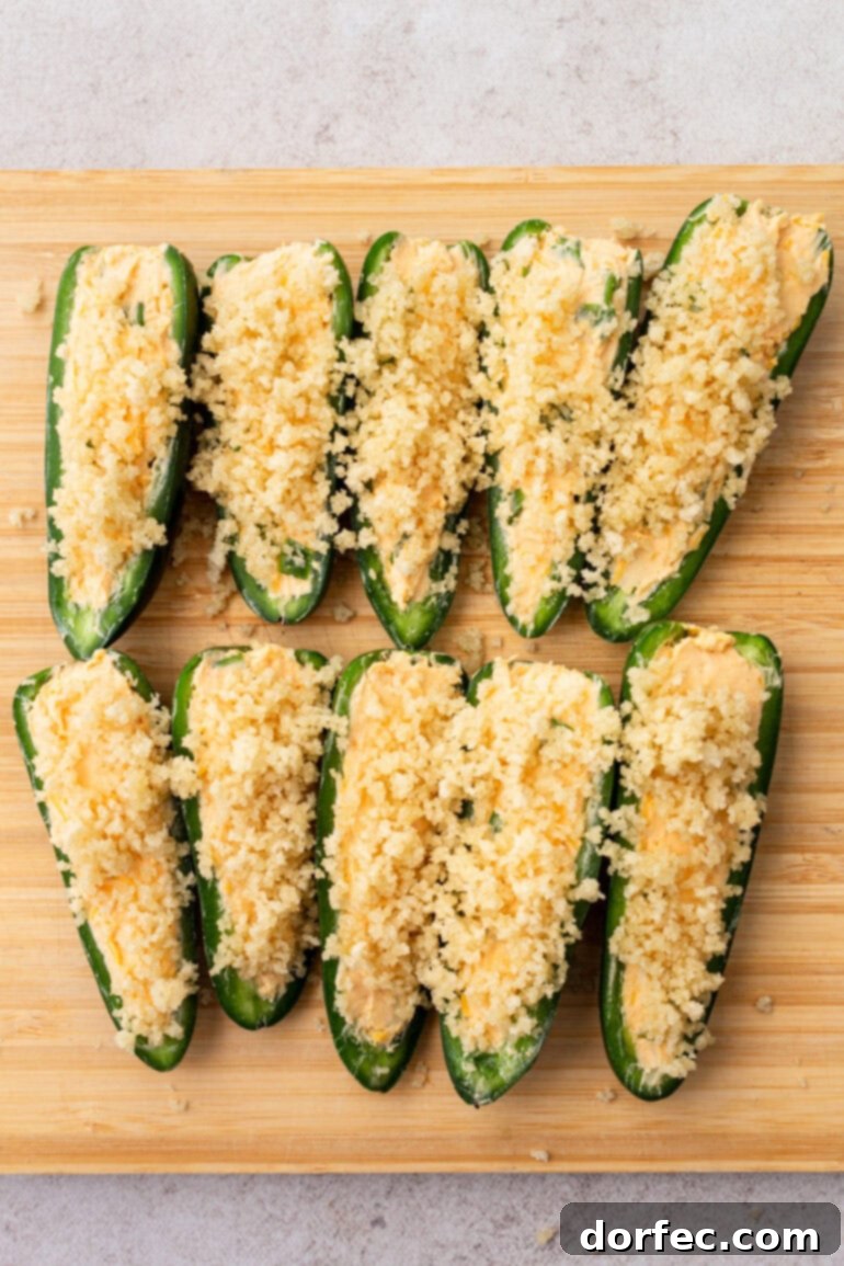 Sprinkling the buttered Panko breadcrumbs generously over the filled jalapeño poppers.