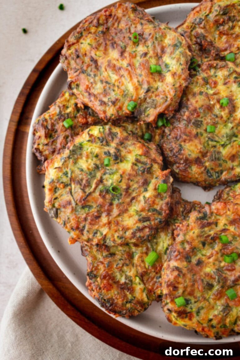 Crispy Parmesan Basil Zucchini Fritters 13 A generous platter filled with numerous crispy golden zucchini fritters, beautifully arranged and ready to be served as a delightful summer dish.