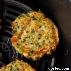 Crispy Parmesan Basil Zucchini Fritters 15 a photo of several golden fried zucchini fritters sitting next to a small cup of creamy dipping sauce