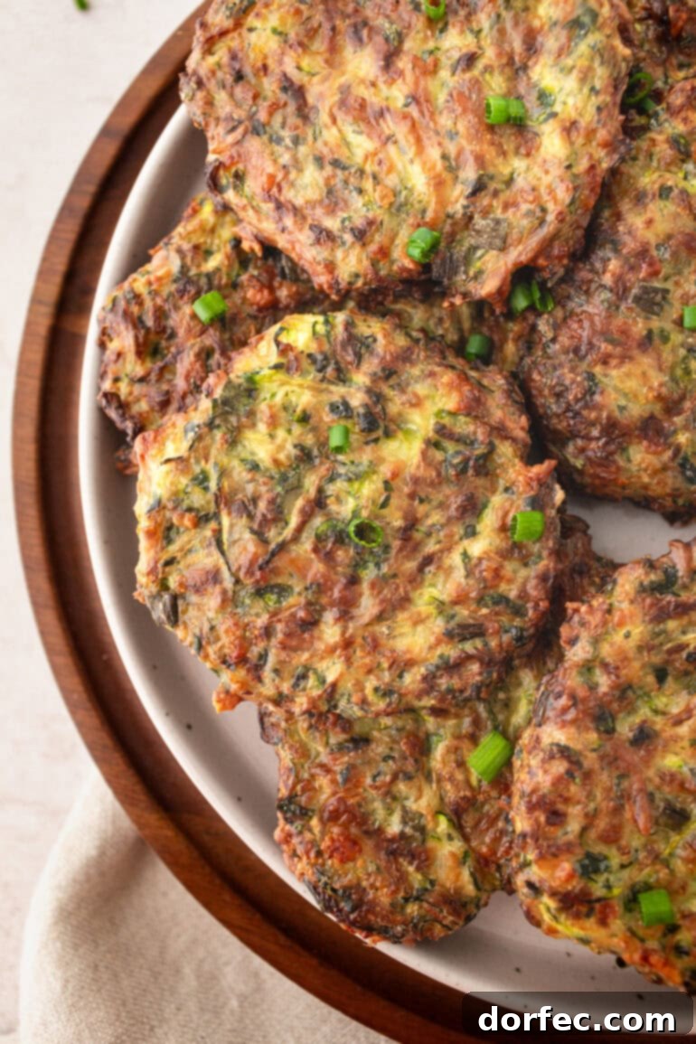 Crispy Parmesan Basil Zucchini Fritters 5 A generously sized serving plate brimming with a golden array of crispy zucchini fritters, ready to be enjoyed as a vibrant summer appetizer or side.