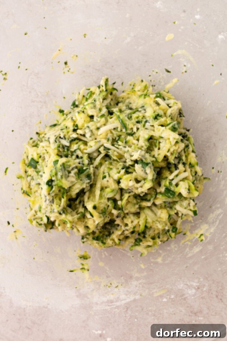 Crispy Parmesan Basil Zucchini Fritters 6 A close-up of freshly grated zucchini, awaiting the crucial step of moisture removal, laying in a colander with a sprinkle of salt.