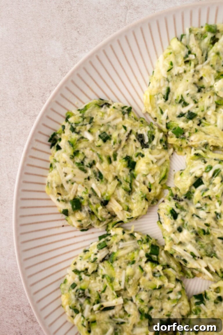 Crispy Parmesan Basil Zucchini Fritters 7 A visual step-by-step image showing grated zucchini being squeezed of excess liquid inside a clean kitchen towel, highlighting the importance of this technique for crispy fritters.