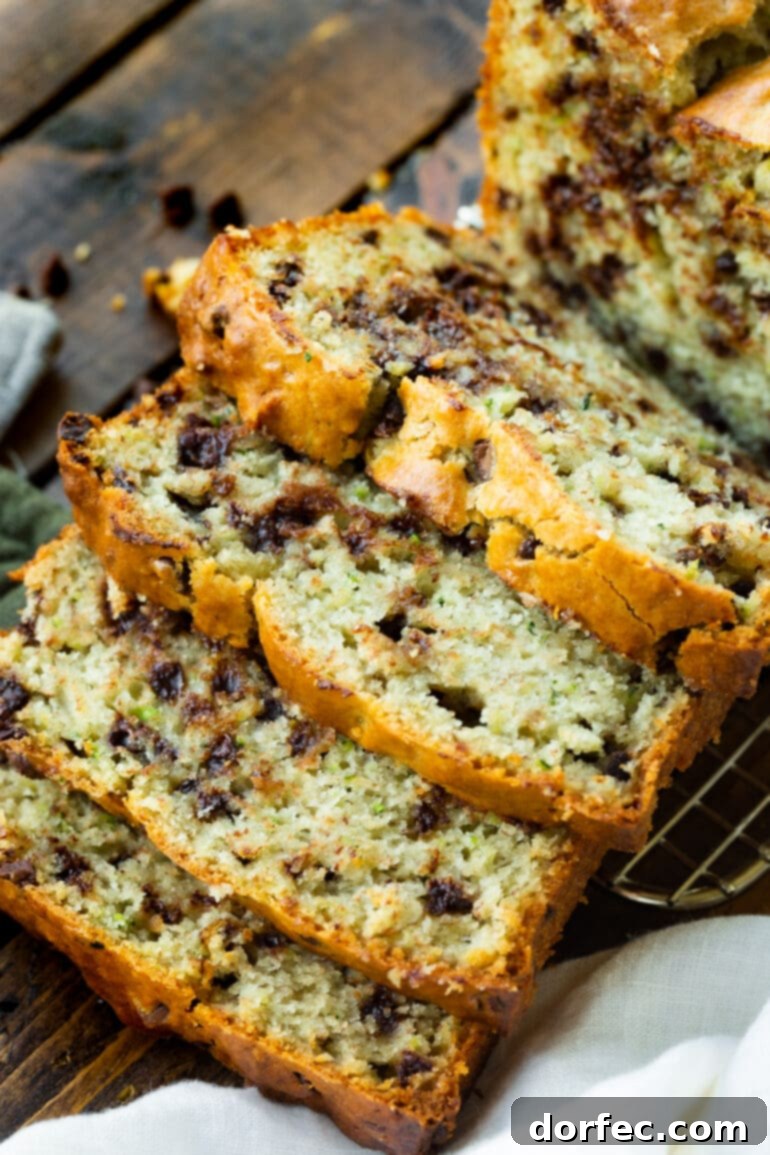 Several slices of moist Chocolate Chip Zucchini Bread, tipped over onto each other, showcasing its rich texture and chocolatey goodness.