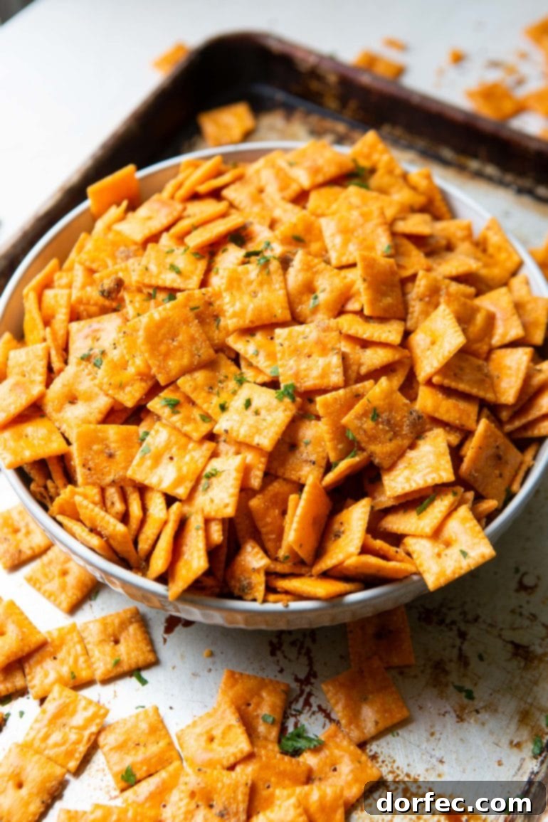 A large white bowl overflowing with seasoned smoked Cheezits, with some spilling over, highlighting their irresistible texture.