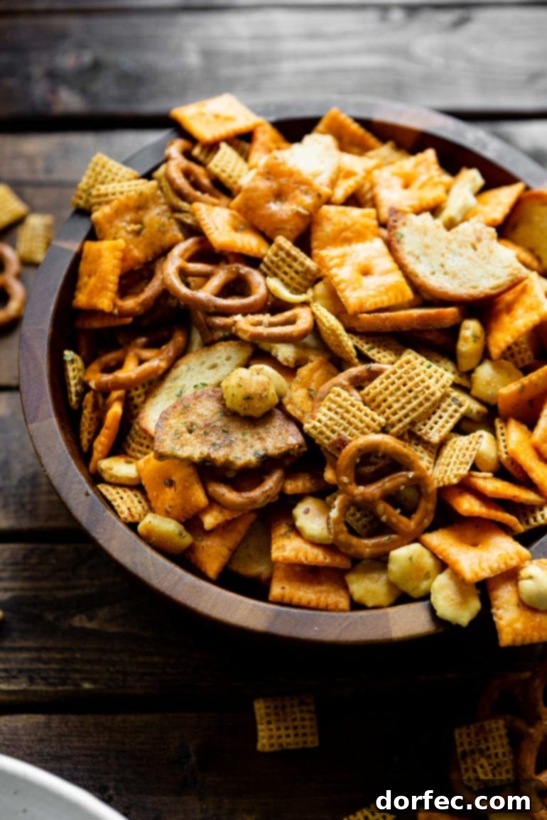 A wooden bowl overflowing with savory Smoked Chex Mix, a delightful blend of cereals, pretzels, Cheezits, and oyster crackers.
