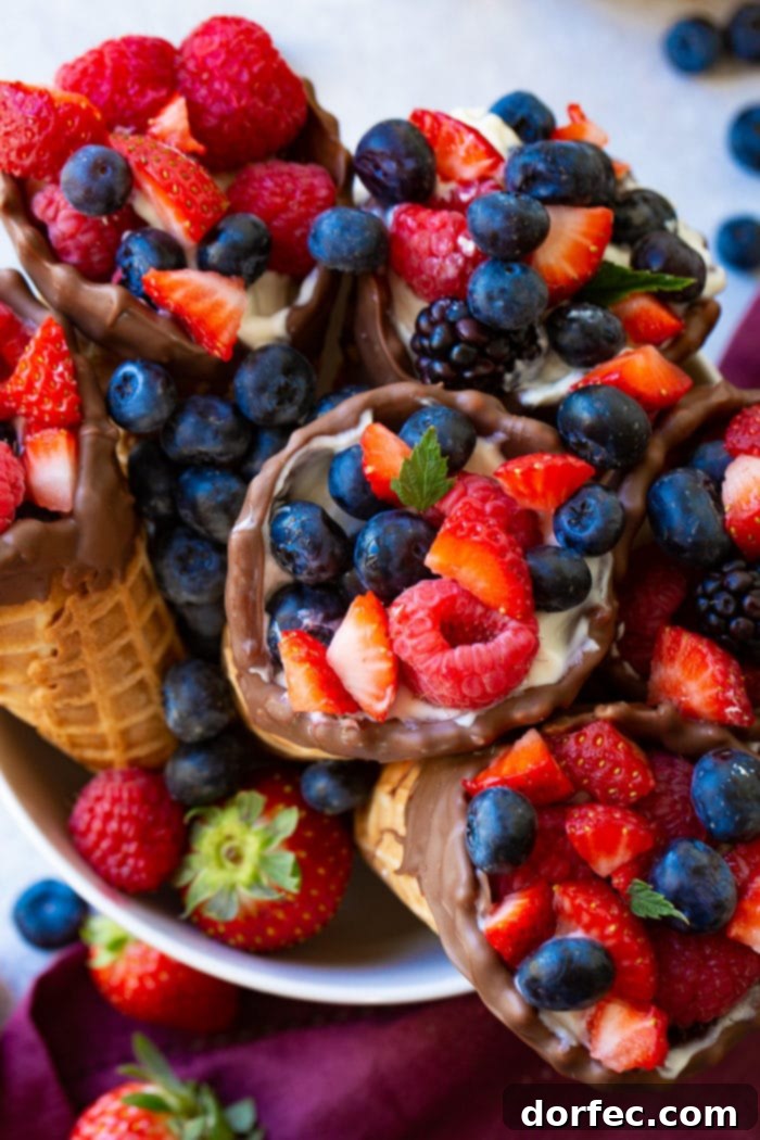 An overhead shot of vibrant Fruit and Yogurt Waffle Cones, filled with fresh fruit and creamy yogurt, served in a white bowl with a purple linen.