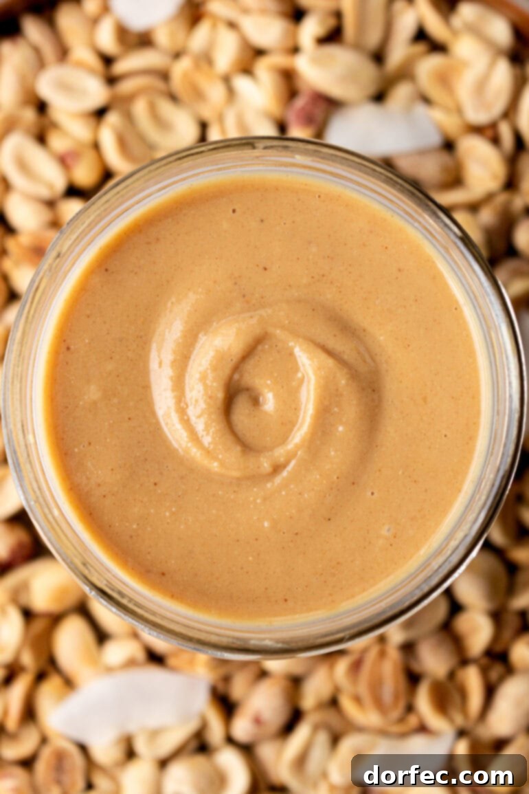 An overhead view of a glass jar brimming with creamy peanut butter infused with coconut, ready to be enjoyed.