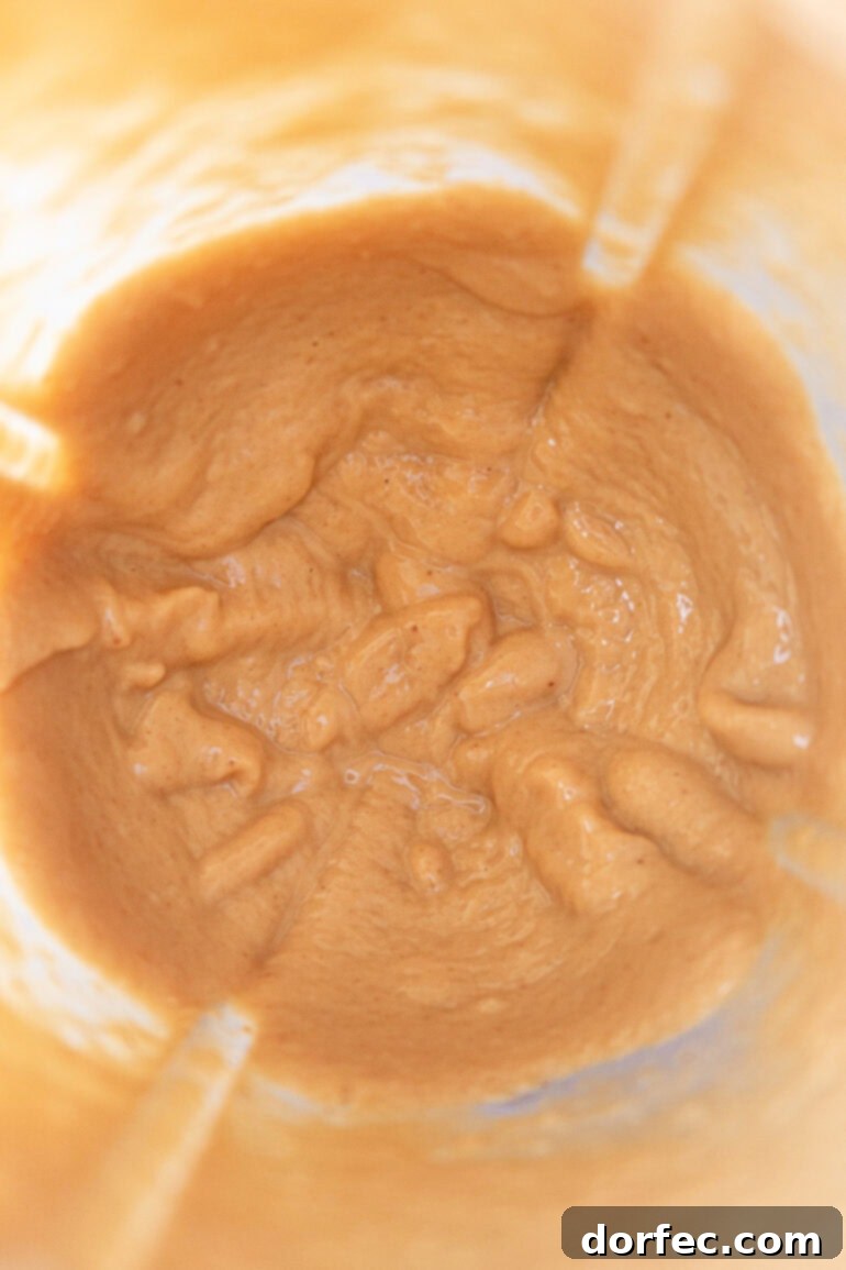 Unsalted dry roasted peanuts being added to the blender with the processed coconut chips.
