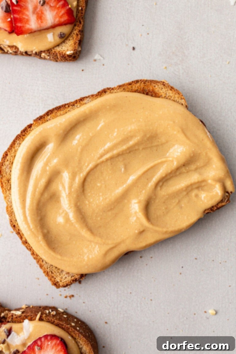 A close-up photo of a piece of toast generously covered with creamy homemade coconut peanut butter, highlighting its smooth and spreadable texture.