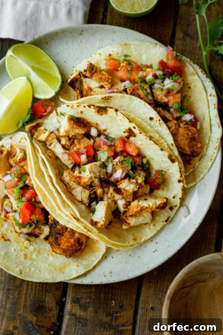 A delectable photo showcasing three grilled chicken tacos, generously filled and beautifully topped with vibrant, fresh pico de gallo, inviting diners to indulge.