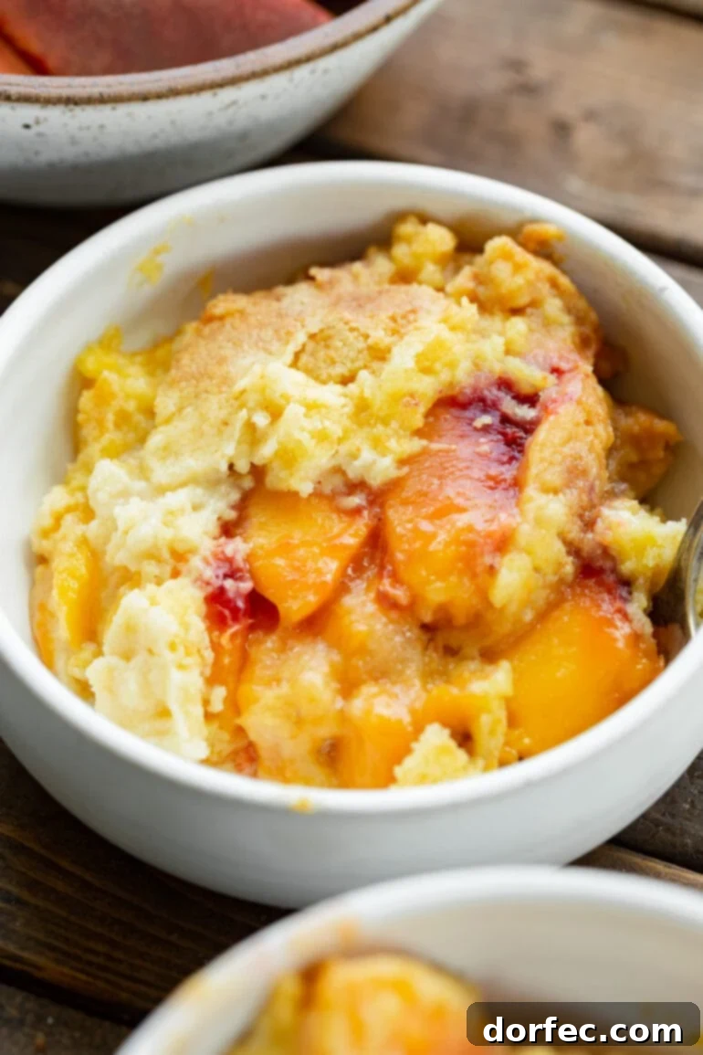A delightful photo of a generous serving of juicy peach cobbler, crowned with a golden, crumbly cake-mix topping, hinting at the warm, sweet flavors within.