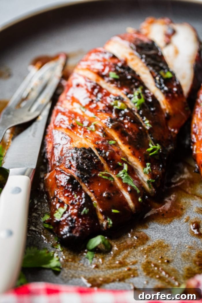 A grey plate with a sliced BBQ chicken sprinkled with parsley