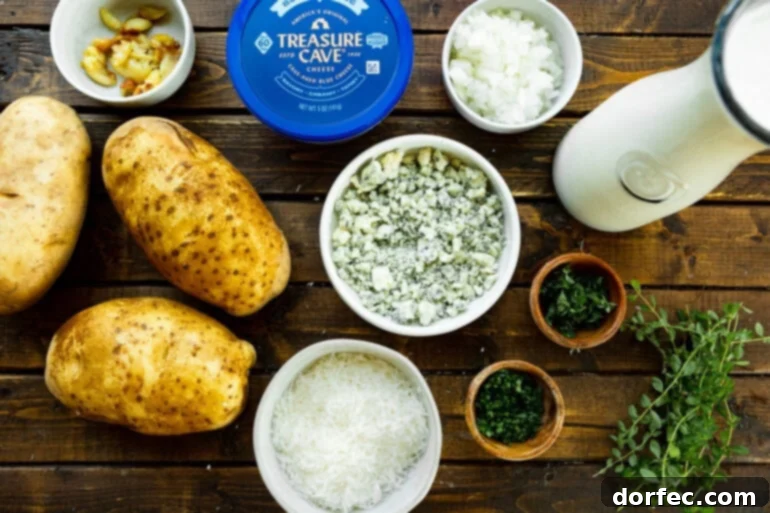 An overhead view of all the fresh ingredients meticulously arranged for making a creamy blue cheese potato gratin, including large russet potatoes, a vibrant block of Treasure Cave blue cheese, fresh thyme and chives, whole garlic cloves, olive oil, salt, and black pepper, ready for preparation.