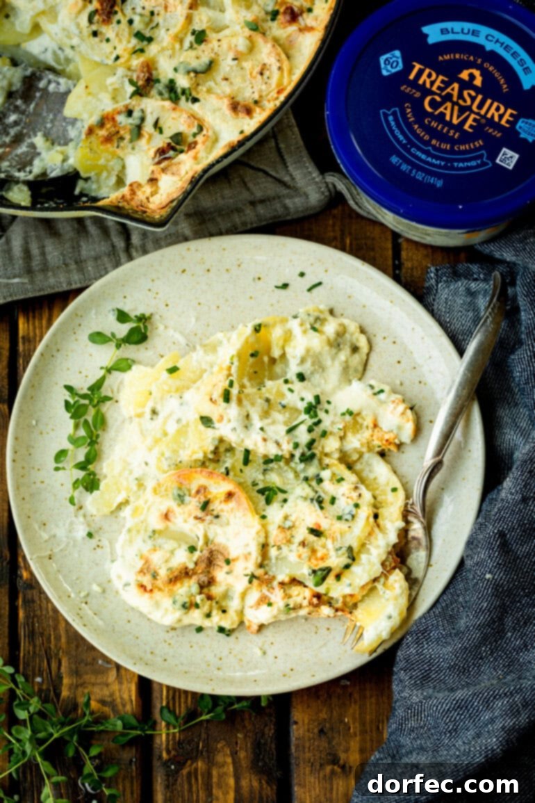 A beautifully plated serving of creamy blue cheese potato gratin on a white dinner plate, accompanied by a fork, highlighting its inviting texture and the rich, cheesy layers, ready to be enjoyed.