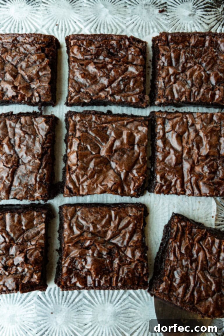 Decadent Box Mix Brownies 4 A close-up photo taken over the top of a pan of perfectly baked brownies, sliced into neat squares, each piece featuring the coveted crinkled top, ready to be enjoyed.