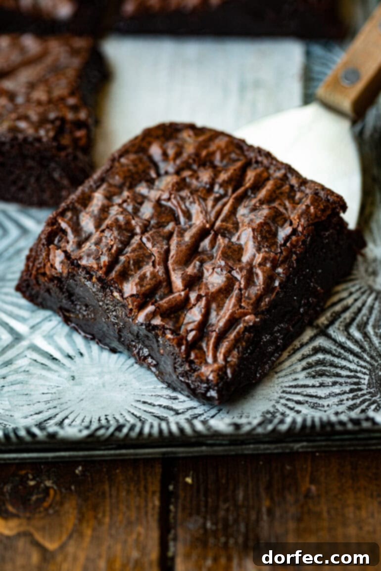 Decadent Box Mix Brownies 5 A close-up photo of a single corner piece of a rich chocolate brownie, showcasing its dense, fudgy interior and the beautiful crinkly top.