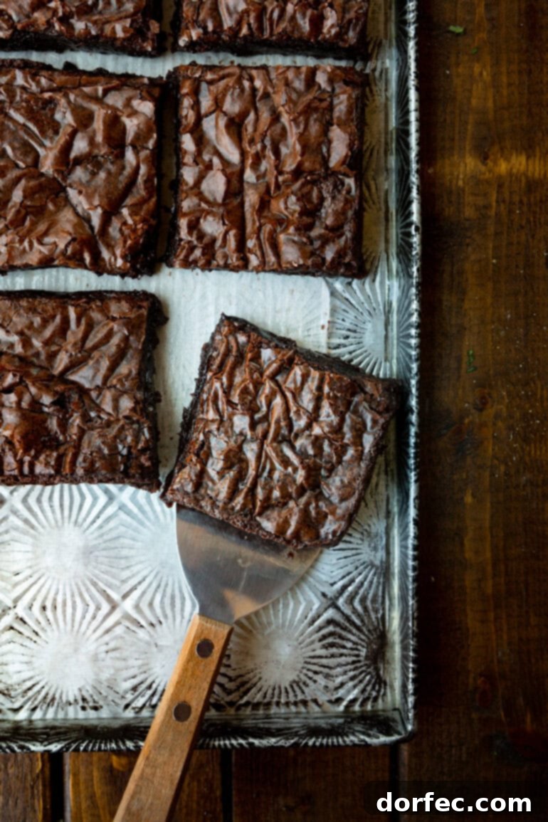 Decadent Box Mix Brownies 6 A small metal spatula is shown carefully removing a perfect slice of chocolate brownie from a pan filled with many others, highlighting the clean cut and fudgy interior.