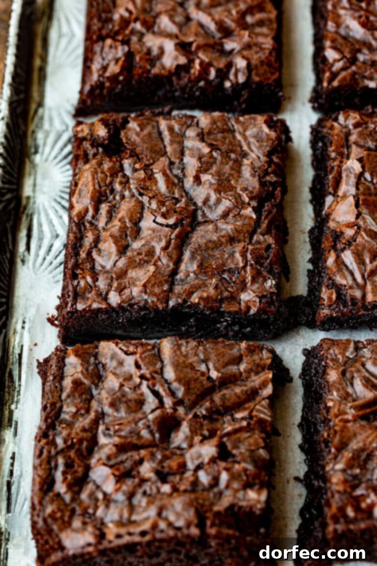 Decadent Box Mix Brownies 8 A close-up photo of several chocolate brownies with distinct crinkly tops, arranged on a plate, highlighting their appetizing appearance.