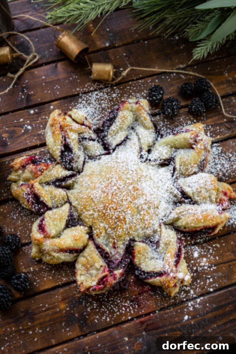 Overhead shot of a baked golden Puff Pastry Snowflake with a vibrant blackberry filling, ready to be served.