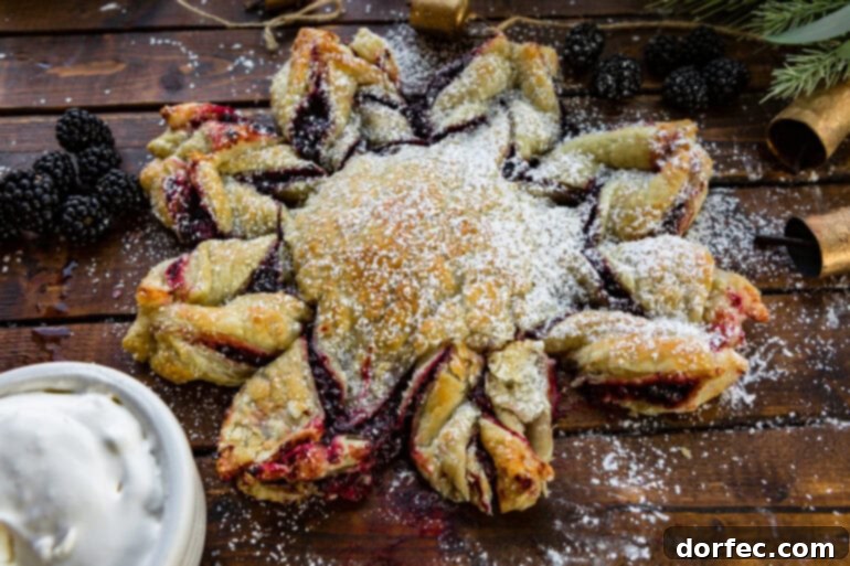 Close-up of a golden-baked Blackberry Puff Pastry Snowflake, lightly dusted with powdered sugar, showcasing its intricate design.