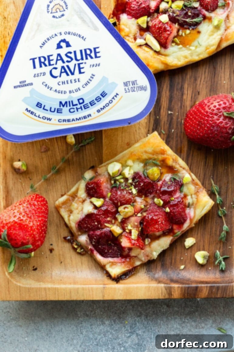 Simple Roasted Strawberry Blue Cheese Tartlets 2 A beautifully baked roasted strawberry tart next to a container of Treasure Cave Mild Blue Cheese, highlighting the key ingredients.