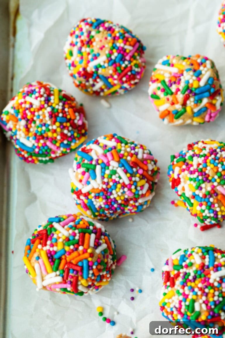 A captivating photo of several perfectly rounded birthday cake protein balls, generously coated in vibrant rainbow sprinkles, ready to be enjoyed.