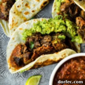 A photo of a shredded beef taco on a flour tortilla and topped with guacamole