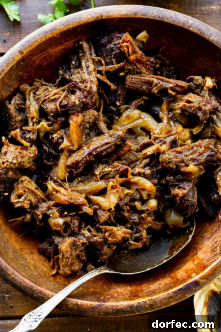A large wooden serving bowl overflowing with tender, juicy shredded beef, seasoned to perfection and ready to be enjoyed.