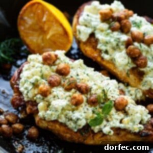 A beautifully plated roasted chicken breast with smashed feta and crispy chickpeas.